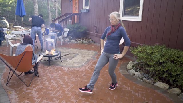 Mature blonde woman practices middle eastern folk dance on her patio.