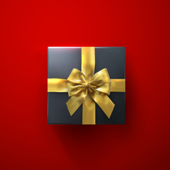 Black gift box with glittering golden bow and ribbons.