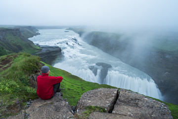 Fototapeta premium Tourist looks at the big waterfall in Iceland