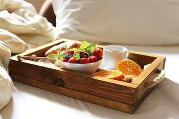 Breakfast in bed with fresh fruits and pastries on a tray. Honeymoon. Morning at the hotel.