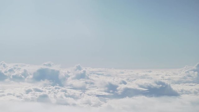 aerial shot from plane flying above the clouds in daytime
