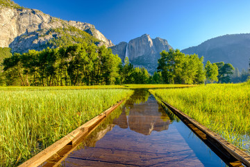 Meadow with flooded boardwalk and Yosemite Falls