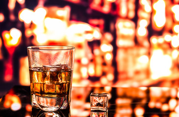 Glass of scotch whiskey and ice on the background of the bar