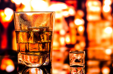 Glass of scotch whiskey and ice on the background of the bar
