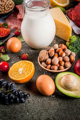 Healthy diet background. Organic food ingredients, superfoods: beef and pork meat, chicken filet, salmon fish, beans, nuts, milk, eggs, fruits, vegetables. Black stone table, copy space