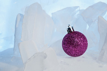 Christmas lilac shiny ball on beautiful blue ice