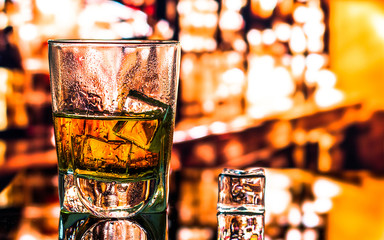 Glass of scotch whiskey and ice on the background of the bar