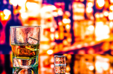 Glass of scotch whiskey and ice on the background of the bar