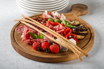 Delicious salami, pieces of sliced ham, sausage, tomatoes, salad and vegetable. Served food menu background.