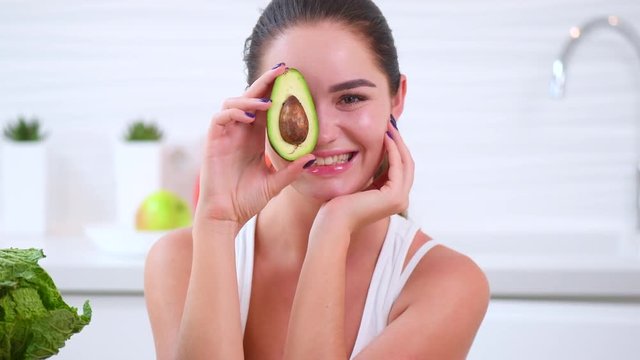 Beauty young joyful woman holding fresh avocado. Healthy eating concept. 4K UHD video footage. Ultra high definition 3840X2160