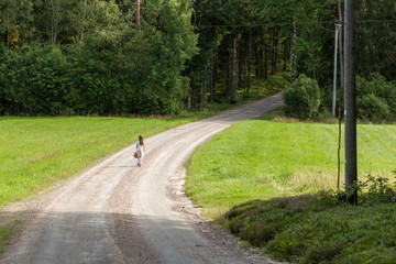 Flicka g&aring;r p&aring; en grusv&auml;g p&aring; landsbygden