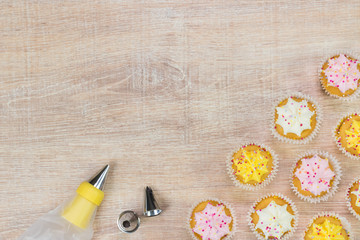 Fototapeta na wymiar Colorful cupcakes and baking tools on a wooden table background.