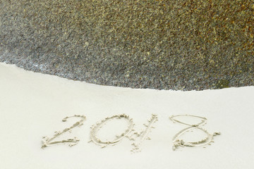 2018 written on the sand with stone of a beach