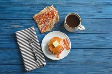 Plate with tasty pancakes and bacon on table
