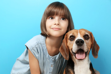Cute girl with dog on color background