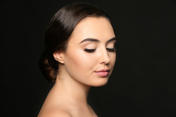 Fototapeta premium Beautiful young woman with eyelash extensions on dark background