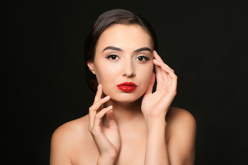 Beautiful young woman with eyelash extensions on dark background