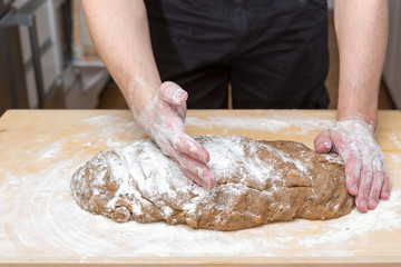 Mann bearbeitet den Teig f&uuml;r die Kekse auf einem Brett