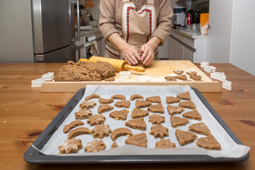 Viele Plätzchen, bereit für den Ofen, liegen auf dem Backblech. Im Hintergrund werden weitere Plätzchen gestanzt