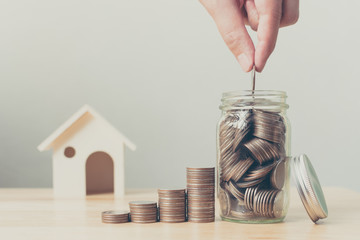 Property investment and house mortgage financial concept, Hand putting money coin stack with wooden house