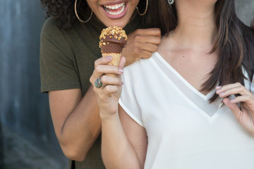 Girl trying to bite other friend's ice cream cone
