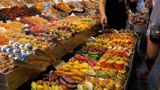 Showcase of Colorful Sweets with Various Assorted Chocolate Candy in La Boqueria Market. Barcelona, Spain. Large counter with various Candy in glaze at Mercat de Sant Josep.