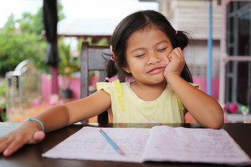 Asian child girl use Pencil write letters on the book.