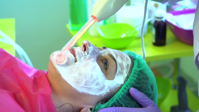 A young girl at a reception with a cosmetologist. Face cleaning. Darsonvalization.