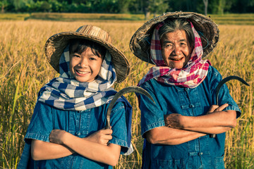 Grandmother and farmer niece with rice harvest.