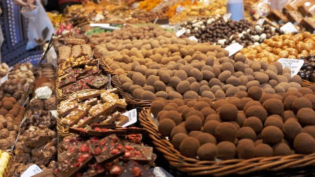 Large Counter of Sweets with Chocolate Candy in La Boqueria Market in Barcelona. Spain. Stall of sweets with Various Assorted Chocolate Candy in glaze at Mercat de Sant Josep.