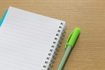 Blank notebook and color pen placed on a brown wood floor.