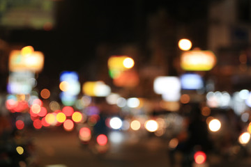 Blurry background of road with roaming cars at night.