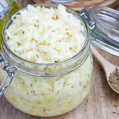 Homemade sauerkraut with cumin in a glass jar, closeup, square