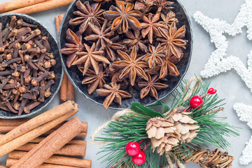 Different kinds of aromatic winter spices in bowls and on table, christmas decoration on gray concrete background, top view