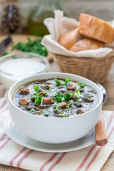 Black bean and ham soup in ceramic bowl on wooden table, vertical