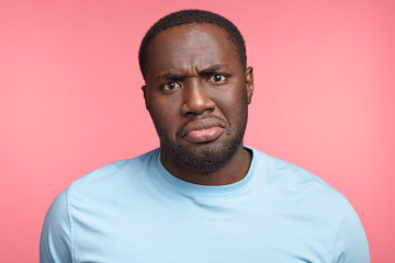 Portrait of discontent black male frowns face in displeasure being unhappy to recieve bad news or...