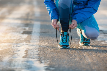 Woman runner tying shoelaces. Healthy lifestyle.