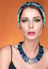 Beauty portrait of beautiful young woman with a kerchief on her head. Necklace on her neck. Makeup and fresh skin