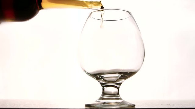 The snifter is being fulfilled with expensive cognac in the luxury restaurant for VIP guest. The beverage has beautiful ginger colour with fire and bronze tones and rich aroma. The liguid is old and