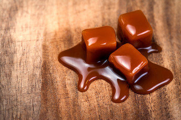 Organic caramel candies and caramel sauce on wooden table, Golden Butterscotch toffee caramels.