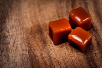Organic caramel candies and caramel sauce on wooden background, Golden Butterscotch toffee caramels.
