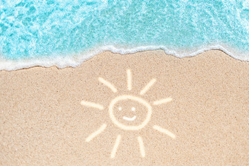 Sea Beach and Soft wave of blue ocean. Summer day and sandy beach background with painted smiling sun as shape lines on sand.