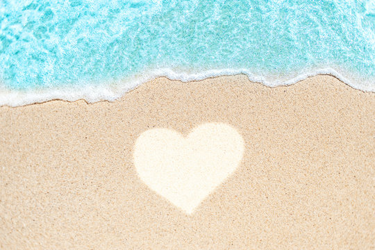 Sea Beach and Soft wave of blue ocean. Summer day and sandy beach background with painted heart  shape lines on sand.