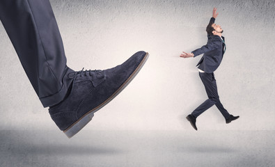 Small businessman kicked by big shoe