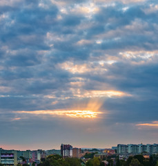 Fototapeta premium the sun's rays make their way through the dark dramatic clouds over the city of Ivano-Frankivsk, Ukraine