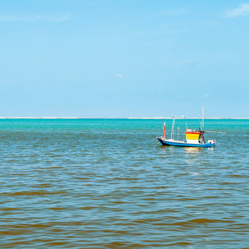 Small Blue Yellow wooden fishing boat in the sea