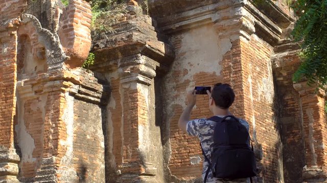 Male Tourist Take Mobile Photo of Ancient Temple Ruins in Asia. Active Trip to Myanmar