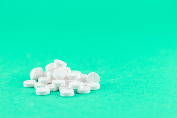 Close up white pills on aquamarine background with copy space. Focus on foreground, soft bokeh. Pharmacy drugstore concept