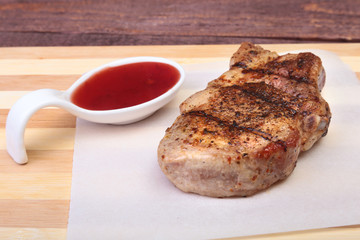 grilled pork chop with Cranberry sauce on plate on wooden board