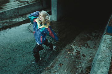 dystopian fashion portrait of model in river of sewage against entrance to tunnel which leads under city
